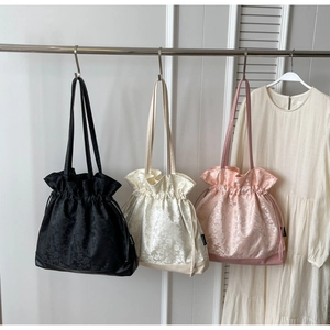Detail of three drawstring tote bags in rose floral jacquard fabric with leather base panels