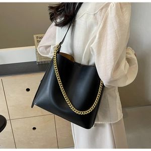 Detail of black leather tote bag with gold chain strap and spacious interior for daily use