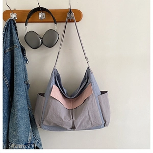 Detail of color-block canvas crossbody bag with multiple utility pockets and hobo design