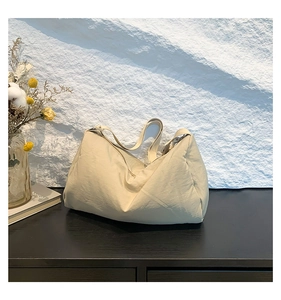 Detail van de zachte crème nylon schoudertas textuur in een minimalistische omgeving