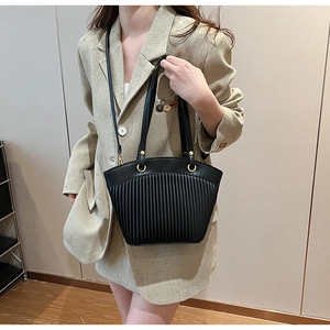 Detail of black tote bag with unique fan-shaped pleated texture and gold hardware