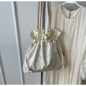 Detailed macro view of beige floral jacquard fabric and reinforced leather bottom on tote bag