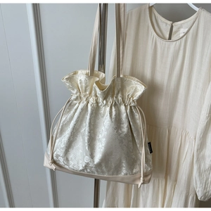 Close-up of floral jacquard fabric and drawstring detail on cream tote bag