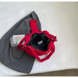 Gros plan d'un cabas en nylon rouge avec compartiments internes et sangle amovible