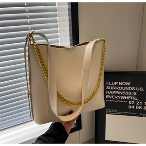 Detail of off-white PU tote bag with gold chain handle and leather strap on white background