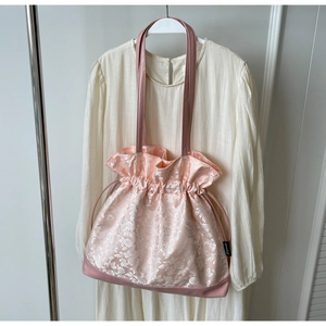 Detailed view of pink drawstring tote with silver floral jacquard and ruffled top edge
