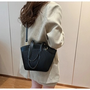 Detailed view of black pleated crossbody bag with premium gold hardware and leather trim
