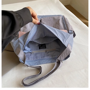 Detail of multi-color nylon messenger bag with striped lining and inner zipper pocket