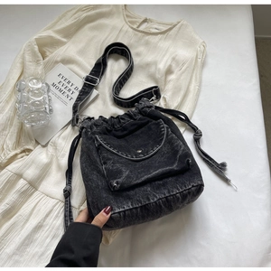 Detailansicht der schwarzen Denim-Beuteltasche mit Kordelzug und Metallschnapptasche