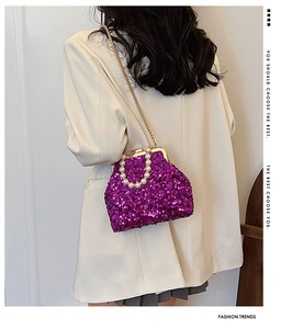 Detail der lila Pailletten-Muscheltasche mit Perlengriff und goldener Kette am Modell