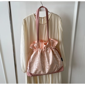 Detail of pink floral satin tote bag with drawstring closure and leather handles