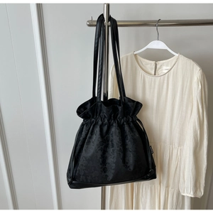 Detail of black jacquard tote bag with drawstring closure and floral texture