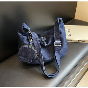 Dettaglio borsa hobo in denim blu con tracolla regolabile e piccolo portamonete rotondo