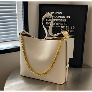 Close-up of cream white tote bag featuring gold chain strap and smooth leather texture