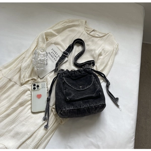 Detail der schwarzen Denim-Beuteltasche mit Kordelzug und Tasche mit Metallschnalle