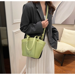 Detail of light green pleated handbag with golden hardware and adjustable crossbody strap