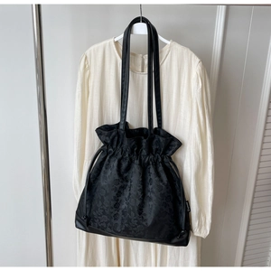 Detail of black jacquard drawstring tote featuring floral texture and leather straps