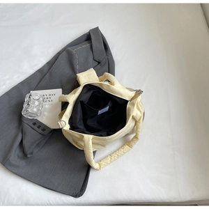 Détail de l'intérieur du sac matelassé en nylon jaune avec poche interne et zip