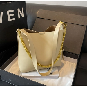 Detail view of cream bucket bag with golden chain and adjustable leather strap in a gift box