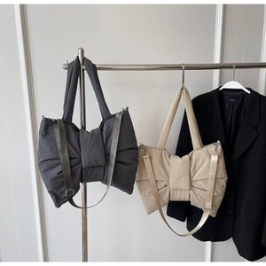 Détail de sacs en nylon gris et beige avec nœud et bandoulières réglables
