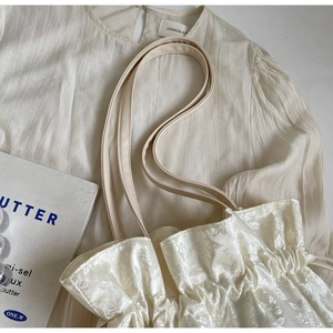 Detail of cream floral jacquard tote bag featuring ruffled drawstring and satin texture