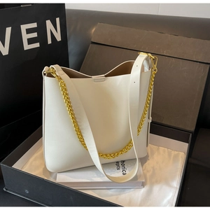 Detail view of cream leather tote bag with gold chain strap and smooth texture