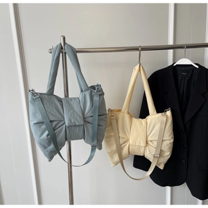 Détail de sacs fourre-tout en nylon bleu et jaune en forme de nœud sur des cintres en métal