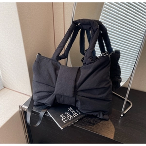 Détail du sac à bandoulière matelassé noir avec nœud et texture en nylon brillant