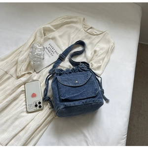Detailansicht einer blauen Denim-Beuteltasche mit Kordelzug und Textur der Pattentasche