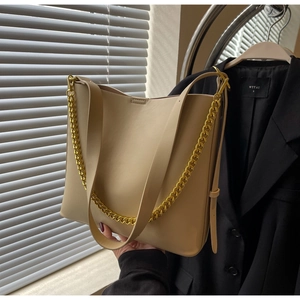 Detail of beige large tote bag featuring gold chain strap and smooth matte leather finish