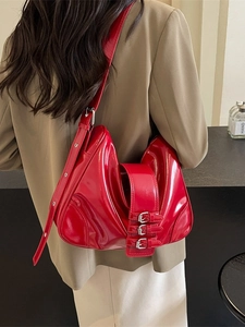 Retro red patent leather hobo bag with silver buckles shown on model shoulder