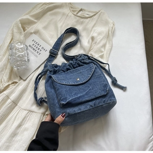 Detailansicht der Denim-Beuteltasche mit Kordelzug und Frontklappentasche auf Stoff