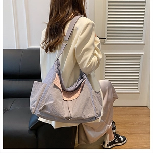 Detail of grey-purple nylon tote bag with wide strap and contrasting pink pocket on model
