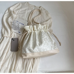 Detail of floral jacquard fabric and drawstring closure on a beige minimalist shoulder bag
