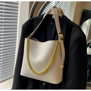 Close-up of cream leather tote bag featuring chunky gold chain and adjustable strap