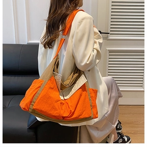 Detailed shot of a large canvas messenger bag in orange and khaki color-block design