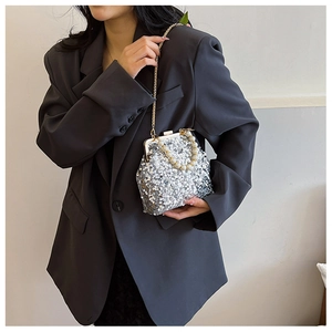 Silberne Pailletten-Clutch mit Perlengriff und Kette getragen zu einem grauen Blazer