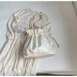 Detail of cream drawstring tote bag with floral jacquard texture and leather base