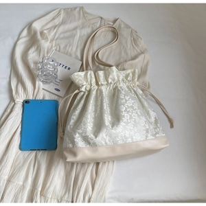 Close-up of cream floral jacquard tote bag with drawstring and matching leather strap