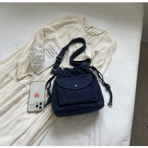 Detail der blauen Denim-Beuteltasche mit Kordelzug und Frontklappentasche auf Stoff