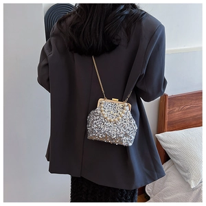 Details einer glänzenden silbernen Pailletten-Tasche mit Perlen Griff und Goldkette
