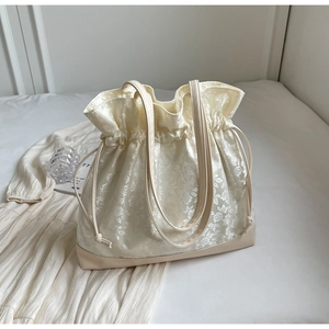 Detailed close-up of cream floral jacquard fabric tote with drawstring and leather bottom