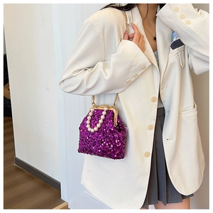 Detailansicht der lila Pailletten-Muscheltasche mit Perlengriff getragen von Model
