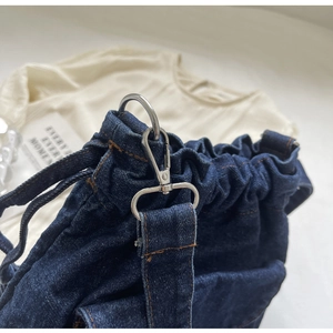 Detailaufnahme der silbernen Karabiner und D-Ringe am blauen Denim-Rucksack für Damen