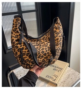 Close-up of leopard print crescent bag with black wide strap on marble tabletop