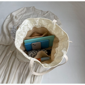 Internal view showing large capacity and drawstring closure of the cream jacquard tote bag