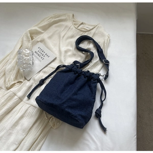 Detail der blauen Denim-Beuteltasche mit Kordelzug und geknoteten Riemenakzenten