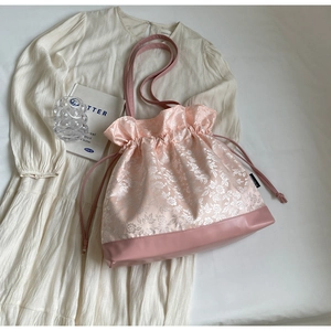 Detail of pink floral jacquard drawstring bag with silky satin finish and leather base