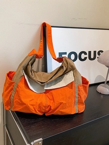 Large orange canvas crossbody bag with khaki accents and side pockets for casual use