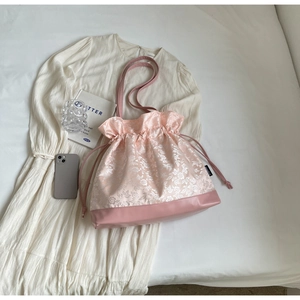 Detail of pink floral jacquard drawstring shoulder bag with a reinforced leather base